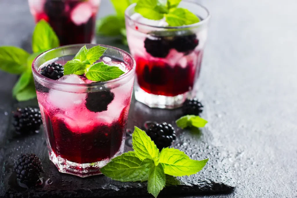 Glass of homemade blackberry juice garnished with fresh mint and blackberries